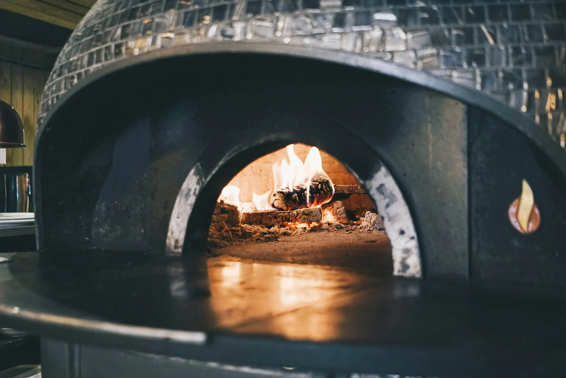 A tiled dome oven glowing with a wood fire inside