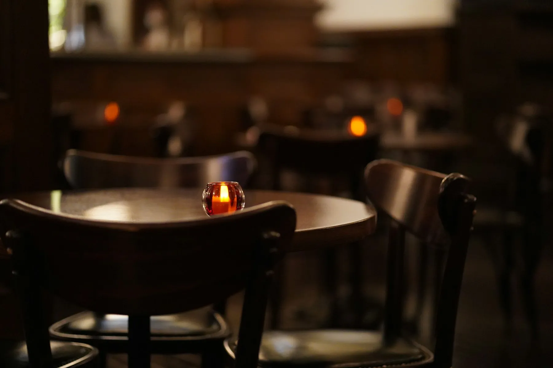 A softly lit dining room with a candle glowing on a round table